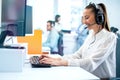 Dedicated smiling woman in headset using computer in office. Call center, customer service support concept.