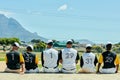 Dedicated sportsmen. Rearview shot of a team of unrecognizable baseball players sitting together near a baseball field