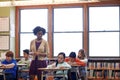 Dedicated to her profession. a group of elementary children writing a test while a teacher observes.