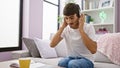 Dedicated young hispanic man, a handy call center agent working from home, settled on his comfy sofa Royalty Free Stock Photo