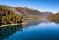 Deep blue lake reflecting sky and vegetation.Mountains in the back