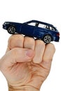 Deep blue metallic model of modern wagon car placed on raised fist of adult male person, white background