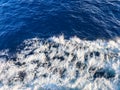 Deep blue ocean water with a layer of white, frothy waves indicating movement, possibly from a boat or ship. T Royalty Free Stock Photo