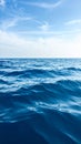 Deep blue ocean waves under a bright sky with wispy clouds reflecting sunlight Royalty Free Stock Photo