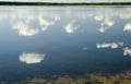Deep blue summer sky with white clouds reflecting in pure lake w Royalty Free Stock Photo