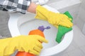 Close up hand with detergent cleaning toilet bowl in bathroom. Man in yellow rubber gloves cleaning toilet seat with green cloth. Royalty Free Stock Photo