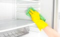 Deep Cleaning service. House cleaning. Washing fridge. Woman hand in yellow rubber protective glove cleaning white open empty Royalty Free Stock Photo