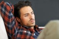 Deep contemplation. A gorgeous young man lying on a sofa with his arm behind his head. Royalty Free Stock Photo