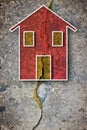 Deep crack in old brick wall with damaged plaster and colored house drawn on it - concept image with copy space Royalty Free Stock Photo