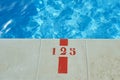 Deep end of a pool with sign marking deepness. Outside swimming pool at warm season Royalty Free Stock Photo