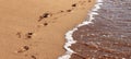 Deep footprints of human bare feet on a beach