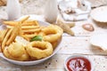 Deep fried calamari, squid rings in tempura and fries, in a bowl, on a white wooden background. Royalty Free Stock Photo