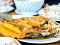 Deep-fried crispy fish with fish Sauce on a white plate and wooden table. Thai food and crusine