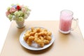 Deep-fried dough stick with pink cold drink and flower in jar on