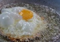 Deep Fried egg in hot foaming oil in the pan in the kitchen Royalty Free Stock Photo
