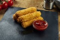 Deep fried mozzarella cheese sticks with red sauce on a black plate. Traditional beer snack. Close up, selective focus Royalty Free Stock Photo