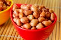 Deep fried peanuts in a red bowl on the bamboo table Royalty Free Stock Photo