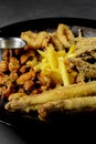 Deep fried set made from french fries, onion rings, big and small fried fish served in a wok over black background. Royalty Free Stock Photo