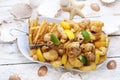 Deep fried shrimps, prawns and squid rings in tempura, with fries, on a white plate, on a white wooden background. Royalty Free Stock Photo