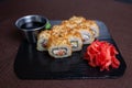 Deep-fried sushi roll with soy sauce and wasabi on a black stone plate Royalty Free Stock Photo