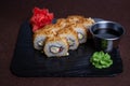 Deep-fried sushi roll with soy sauce and wasabi on a black stone plate Royalty Free Stock Photo