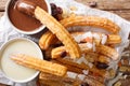 Deep-fried sweet churros served with hot chocolate and condensed milk close-up. horizontal top view Royalty Free Stock Photo