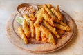 Deep fried whitebait sprats served in a crispy golden batter on a wooden platter serving board with a slice of lime