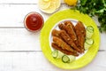 Deep frying small fish capelin on a plate on white wooden background.