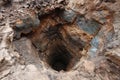 Deep hole in the ground revealing layers of rock, soil, and minerals Royalty Free Stock Photo