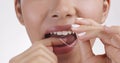 Oral care. Close up shot of young woman flossing her teeth with tooth floss, white studio background, slow motion