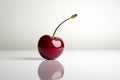 Deep red cherry resting on a reflective surface in minimalist composition Royalty Free Stock Photo