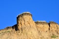 Deep sandy cliff on the background of blue sky.