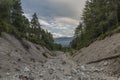 Deep valley of dry creek in dark cloudy summer morning under Mittagskogel hill Royalty Free Stock Photo