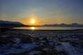 Golden sunrise over blue fjord and snowy mountain with reflection on thick ice Royalty Free Stock Photo