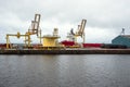 Quayside crane in a commercial port with a moored cargo ship Royalty Free Stock Photo