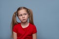 Deeply offended little girl with purse lips and  injured look  against blue background Royalty Free Stock Photo