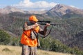 Deer hunter aiming rifle in rugged mountains