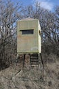 Deer hunting stand in afternoon sunshine with leafless oak trees in background
