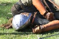 A defeated knight in a metal helmet and armour lies on the ground, costume performance at a medieval fair. South Australia, 2021