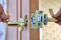 Locksmith is repairing faulty lever door handle with latch. Royalty Free Stock Photo