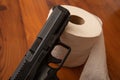 Close up of a pistol laying against toilet paper