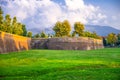 Defensive brick city wall, grass green lawn, trees and Tuscany hills and mountains with beautiful cloudy evening sky background, L Royalty Free Stock Photo