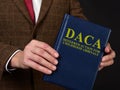 Deferred Action for Childhood Arrivals DACA concept. Man shows the book. Royalty Free Stock Photo