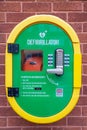 A defibrillator or AED in a secure case on a brick wall in the street