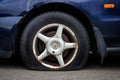 Deflated car tire on a rusted wheel.