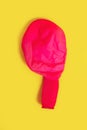 Deflated red balloon on a yellow background Royalty Free Stock Photo