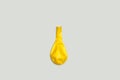 A deflated yellow balloon on a gray background