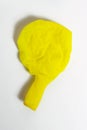 Deflated yellow balloon on a white isolated background Royalty Free Stock Photo