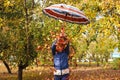 Defocus autumn people. Teen girl holding umbrella and throwing leaves. Many flying orange, yellow, green dry leaves Royalty Free Stock Photo