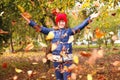 Defocus autumn people. Teen girl raising hand and throwing leaves. Many flying orange, yellow, green dry leaves. Enjoy Royalty Free Stock Photo